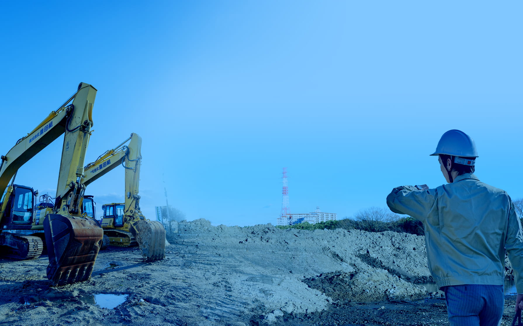 建設現場のショベルカーと作業員の後ろ姿