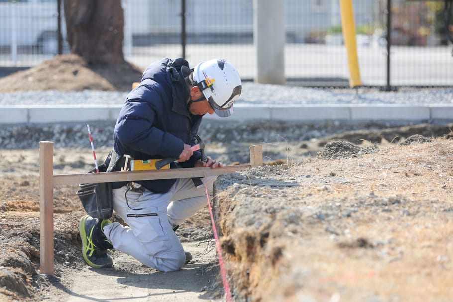 工事現場で作業する作業員が、ヘルメットを着用し木枠を固定している