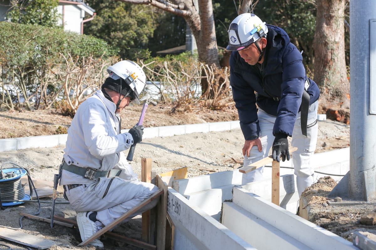 作業着を着た二人のビジネスパーソンが書類を持ち、打ち合わせをしている様子