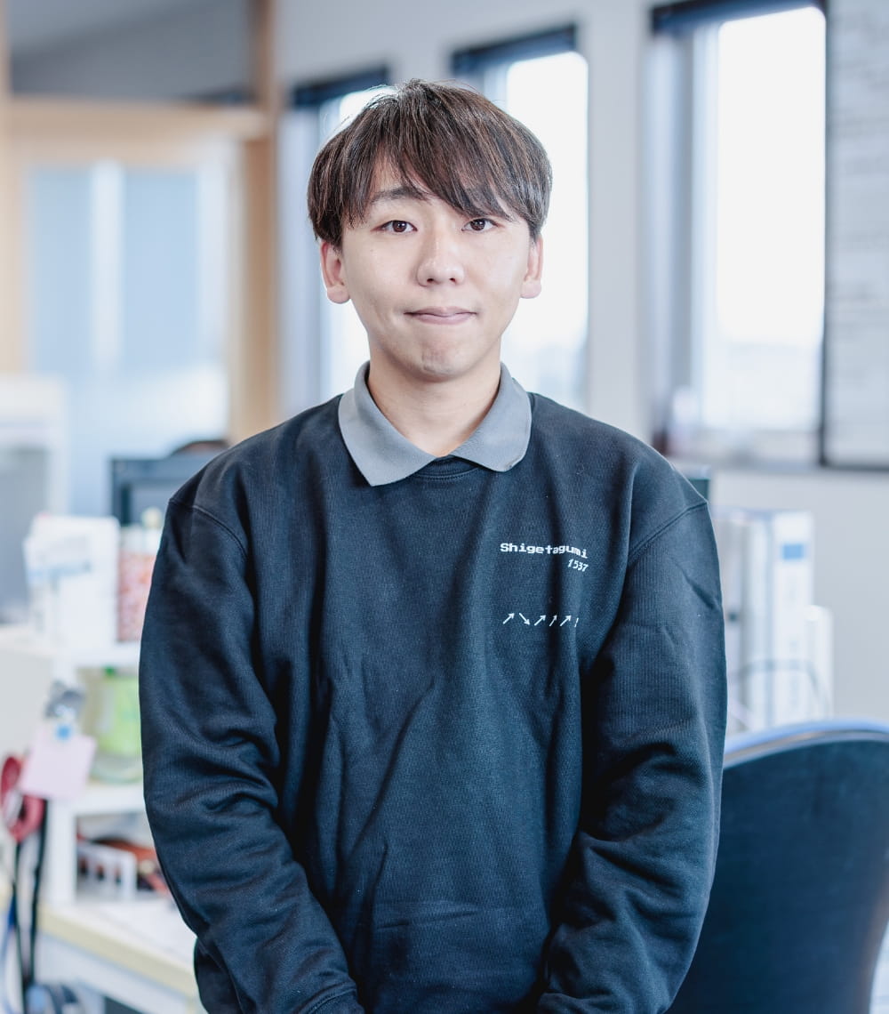 オフィスで黒い制服を着た男性が落ち着いた表情でこちらを見つめる様子